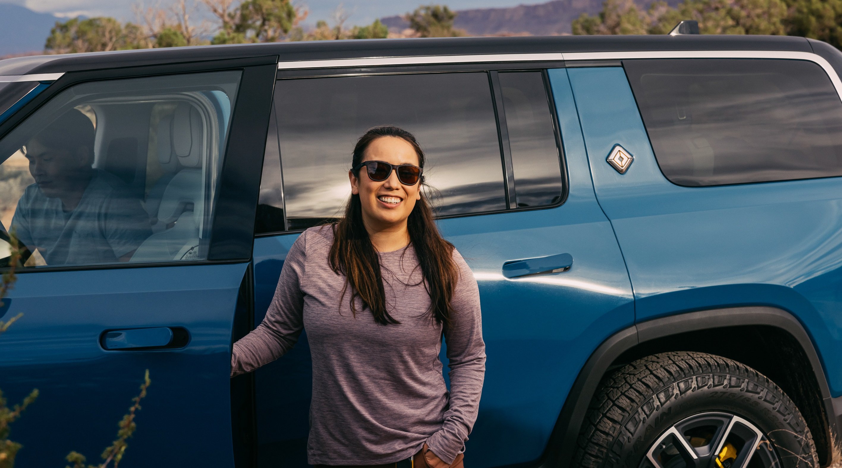 Driver standing beside a 2022 Rivian R1S.