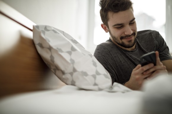 Person using phone in bed.
