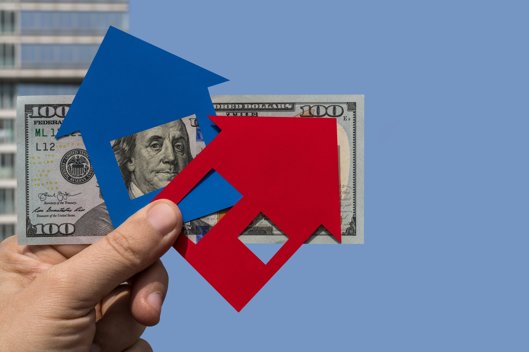 Paper cut outs in the shape of houses in front of a 100-dollar bill.