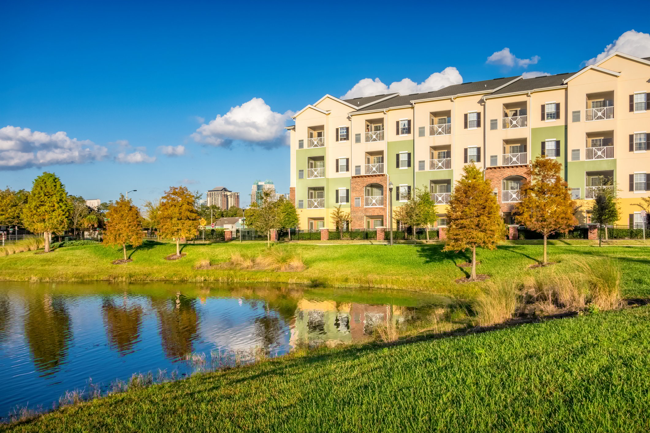 Apartment complex overlooking a small lake with trees.