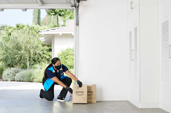 An Amazon delivery carrier leaving a package in a garage.