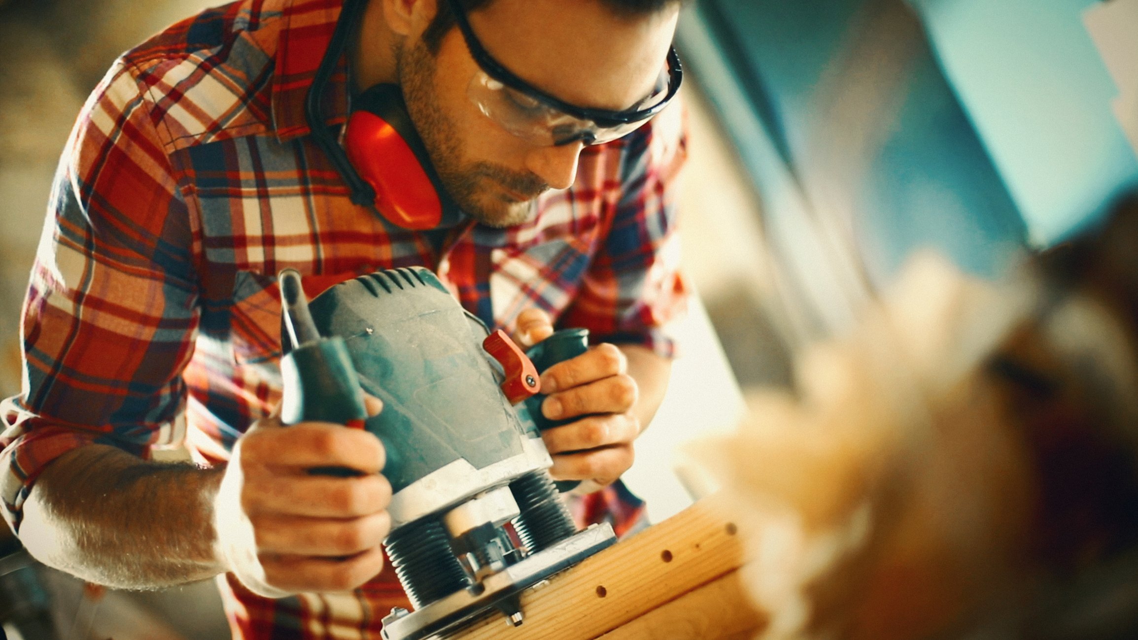 A man working with a plunge router in a workshop.