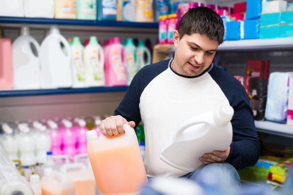 Person choosing cleaning products at a store.