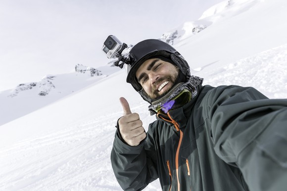 Skier with action camera on helmet is taking a selfie.