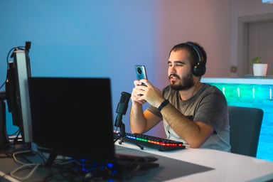 Gamer using smartphone in front of gaming PC
