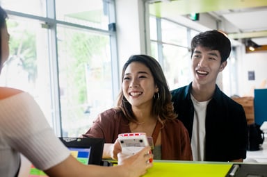 Two people standing at a cashier and paying