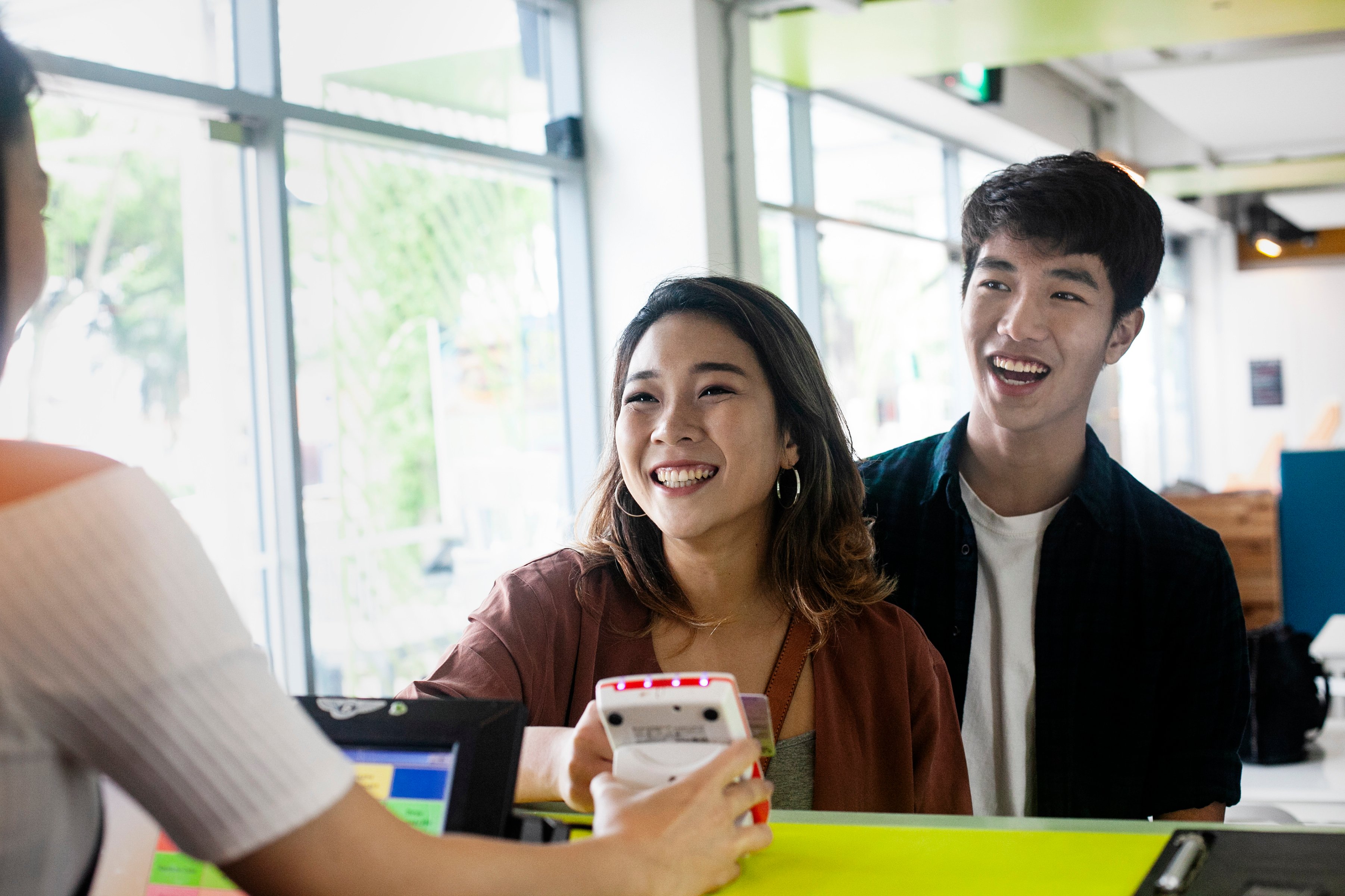 Two people standing at a cashier and paying.