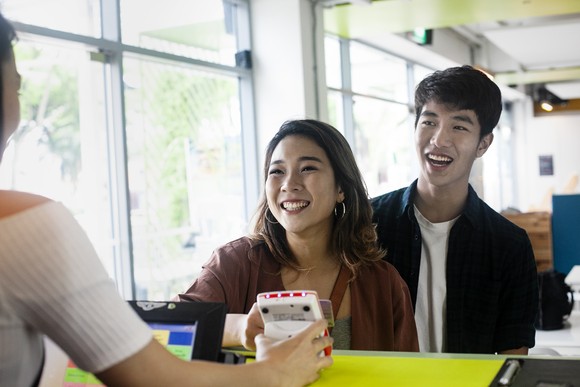 Two people standing at a cashier and paying.