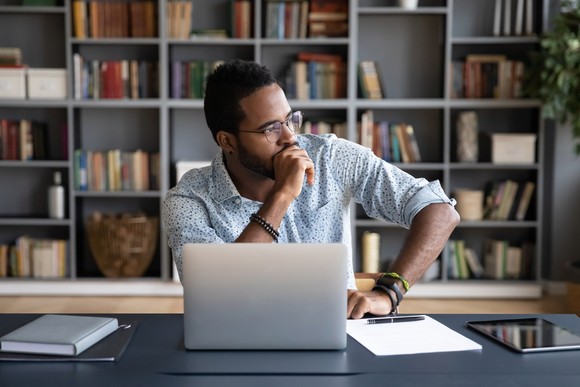 Person in deep thought sitting in front of a computer.