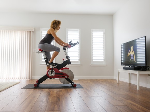 Person riding spinning bike in a room with a TV.