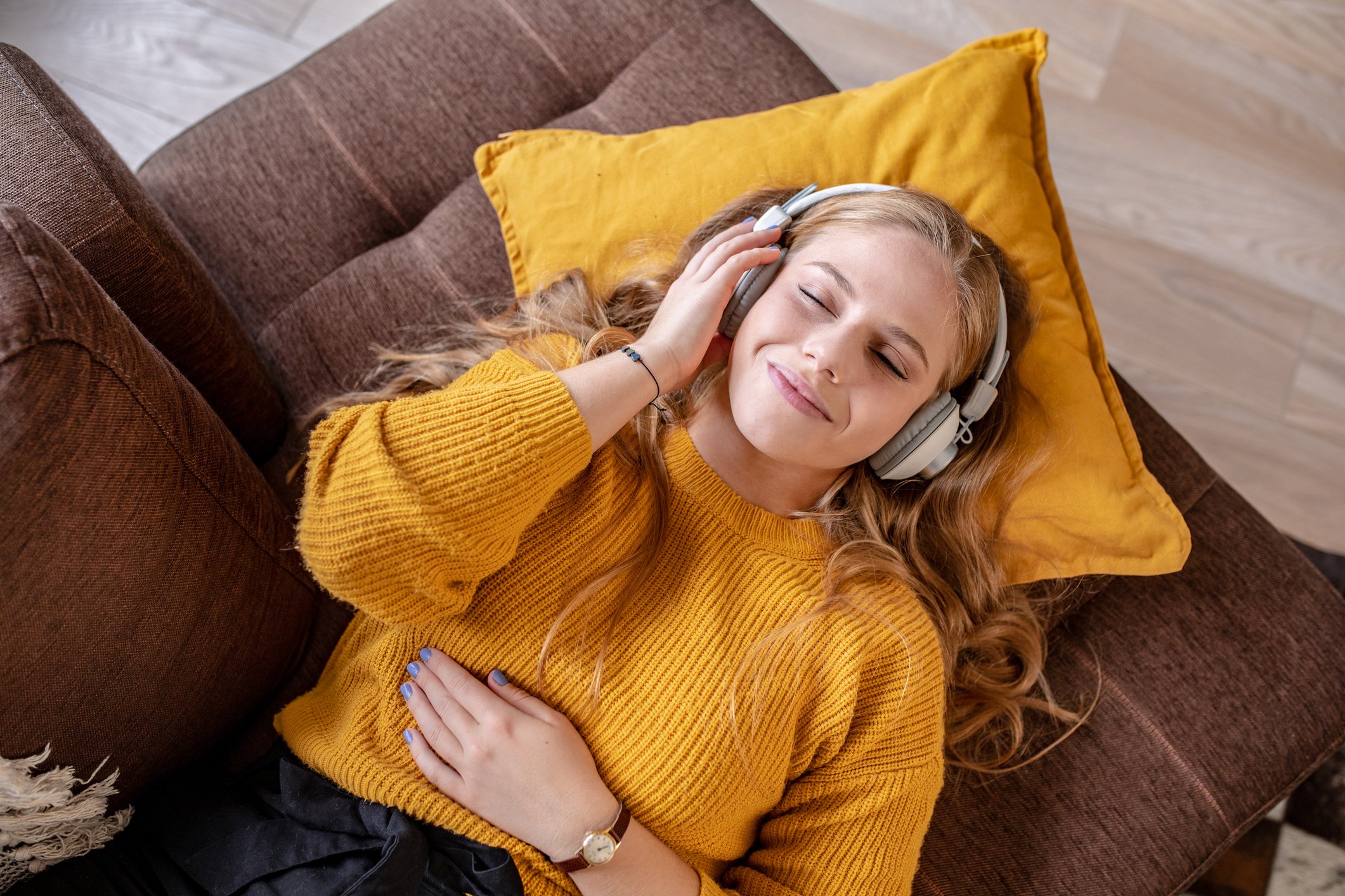 A music listener lying on a couch.