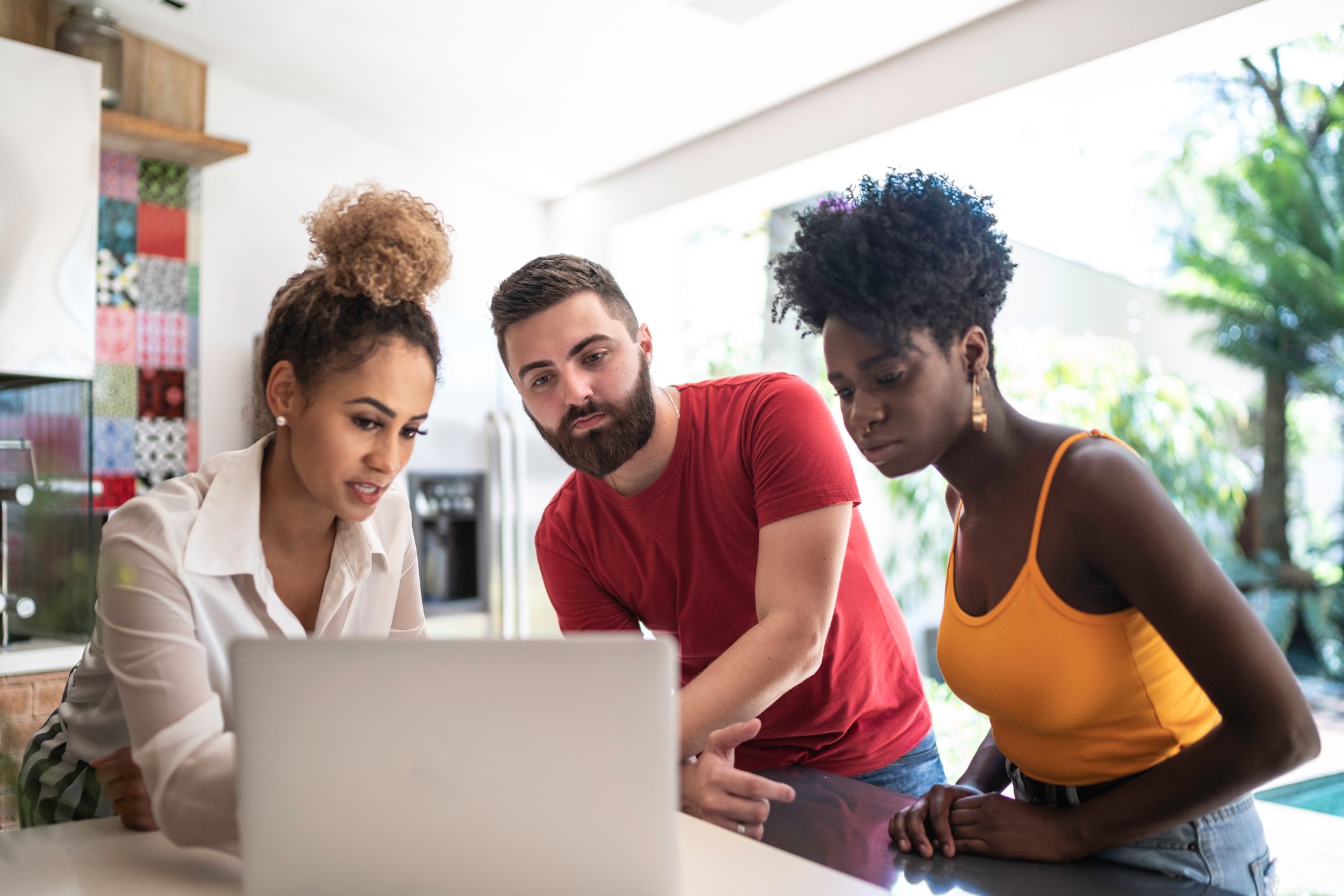Financial advisor conversing with a young couple while she references something on her computer screen.