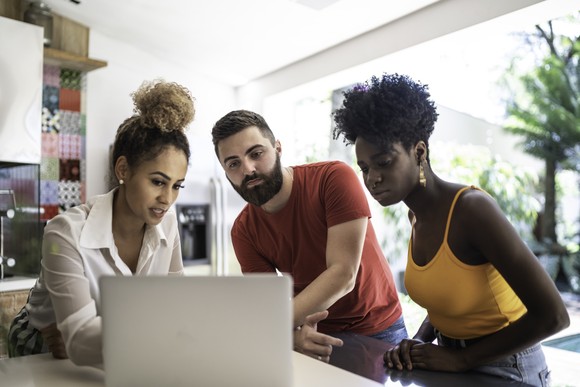 Financial advisor conversing with a young couple while she references something on her computer screen.