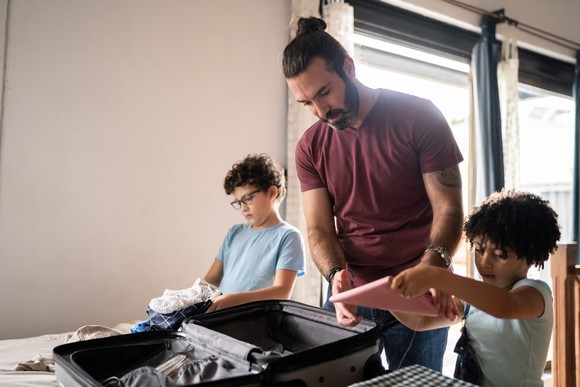 Adults and child packing a suitcase.
