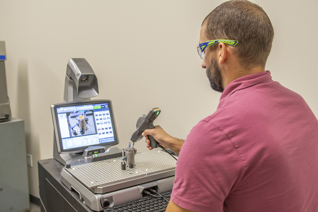 A Proto Labs employee inspecting work on a 3D printing machine. 
