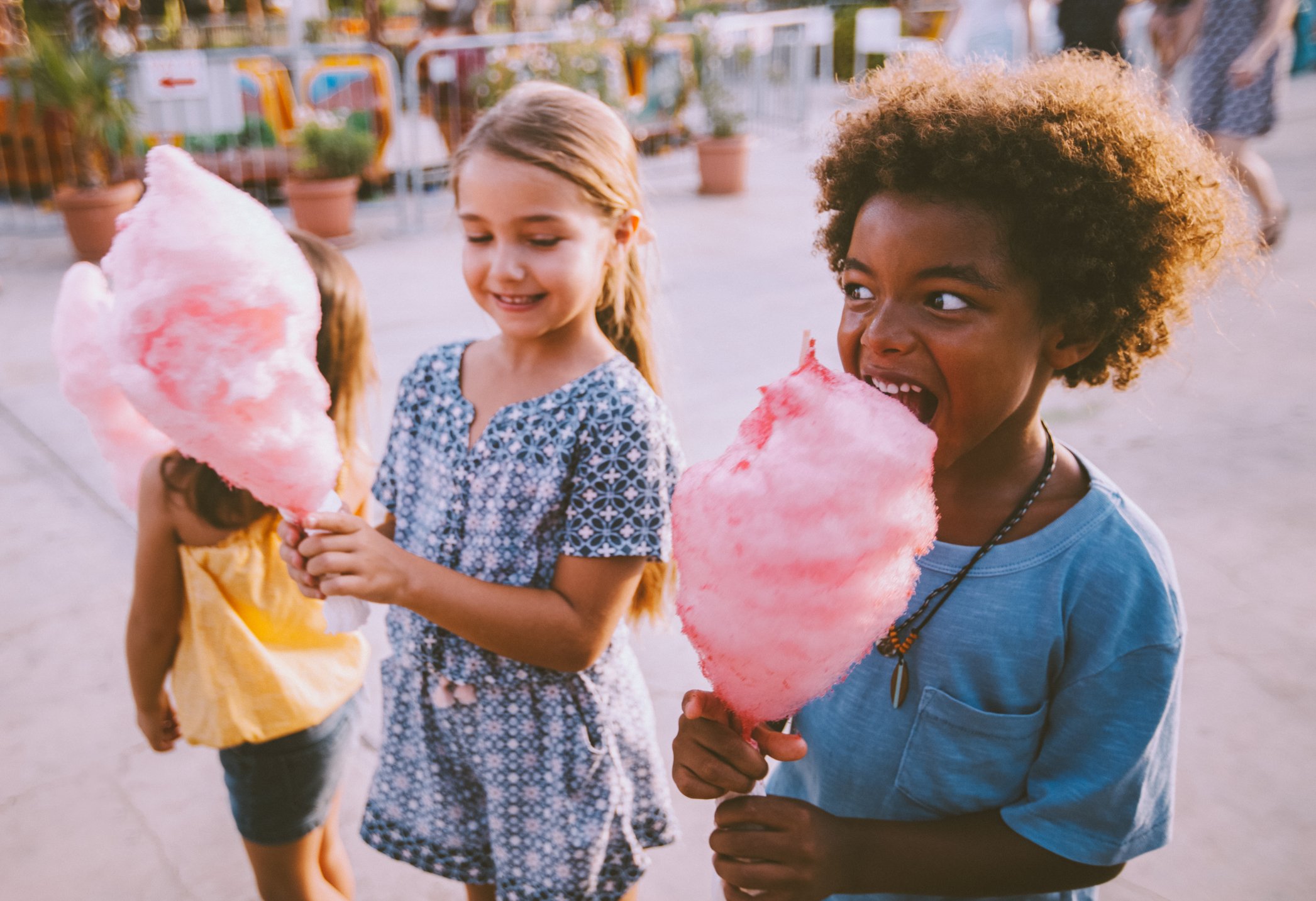Kids eating cotton candy at a theme park.