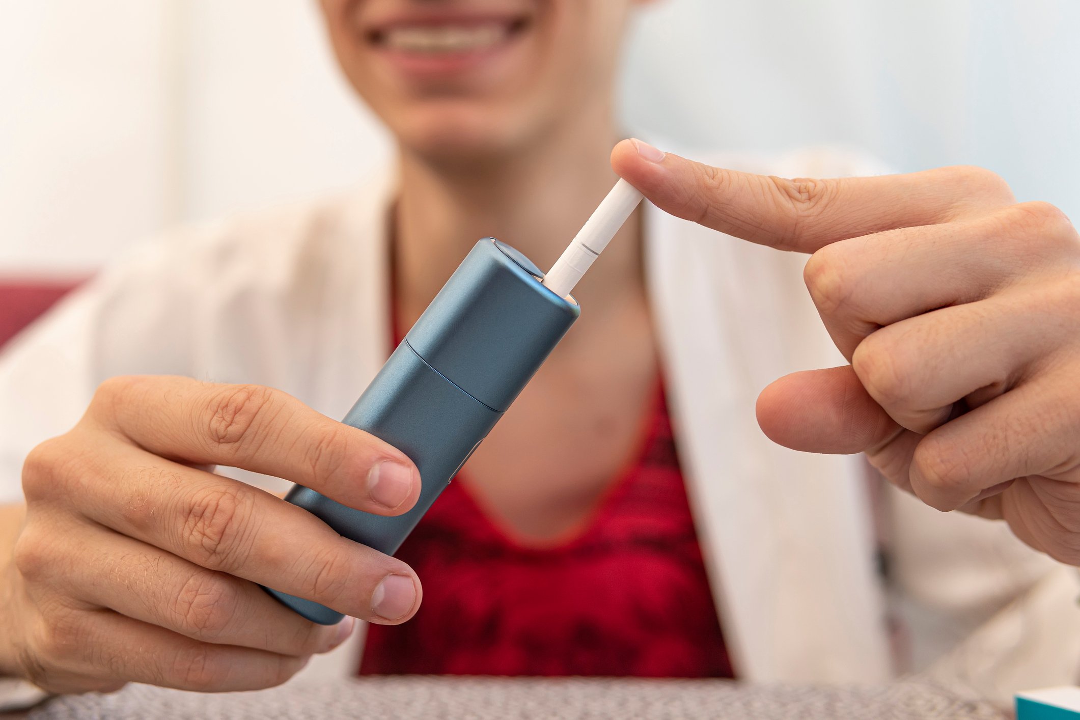 Person loading a tobacco cartridge into a heated tobacco device.