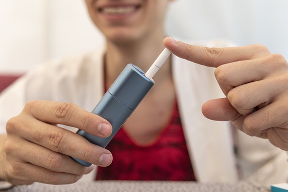 Person loading a tobacco cartridge into a heated tobacco device.