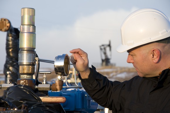 An oilfield worker checks the pressure gauge at a natural gas well. 