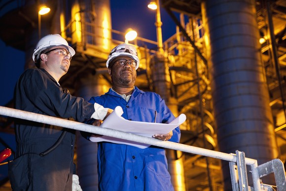 Two workers reviewing plans at an oil refinery
