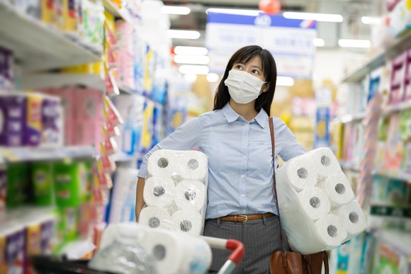 A woman shopping for tissue paper in a grocery store.