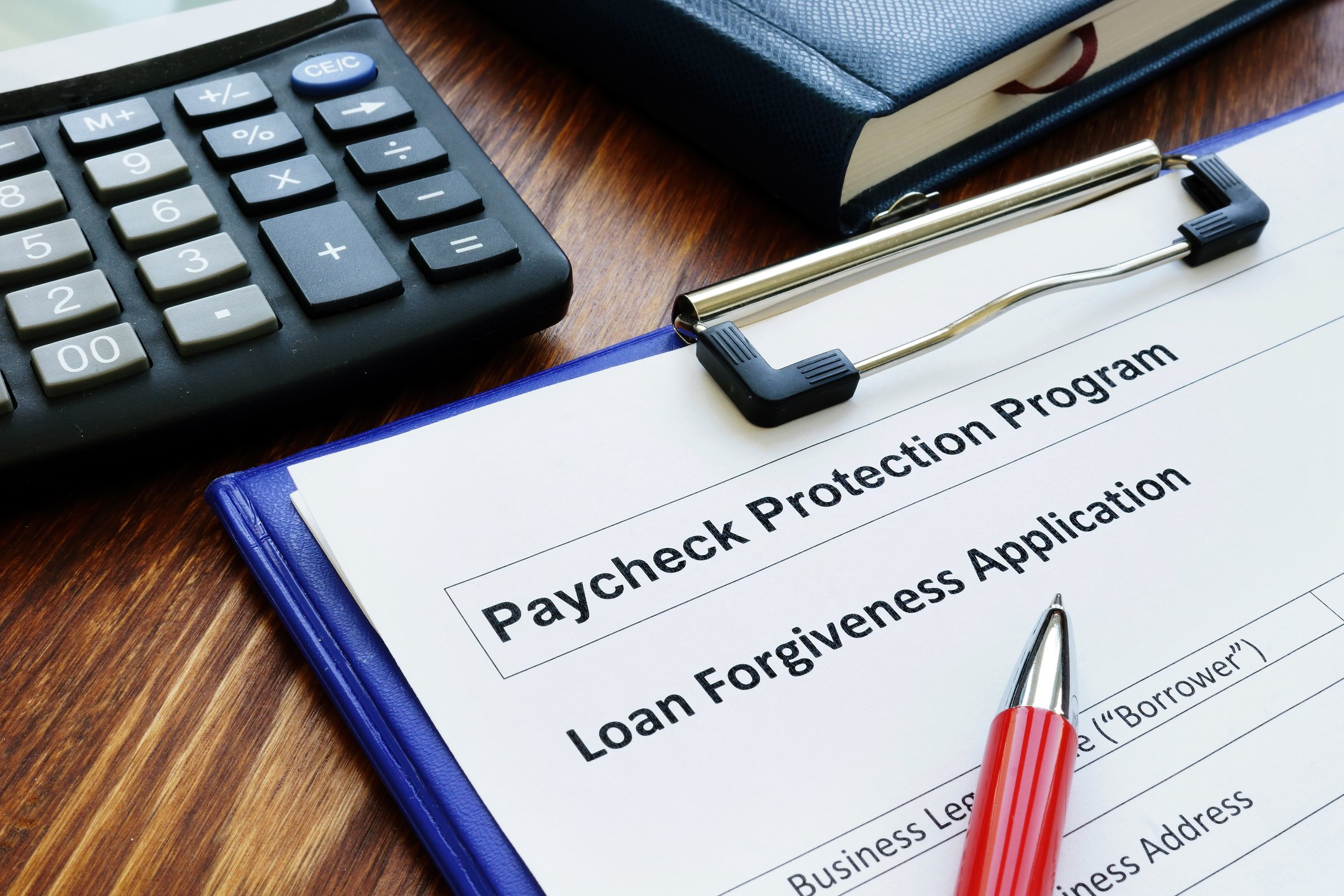 Paycheck Protection Program loan forgiveness application on clipboard with pen.