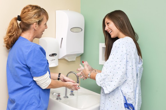 Nurse and patient washing their hands at a sink.