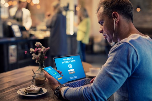 Person doing two-factor authentication between a smartphone and laptop.