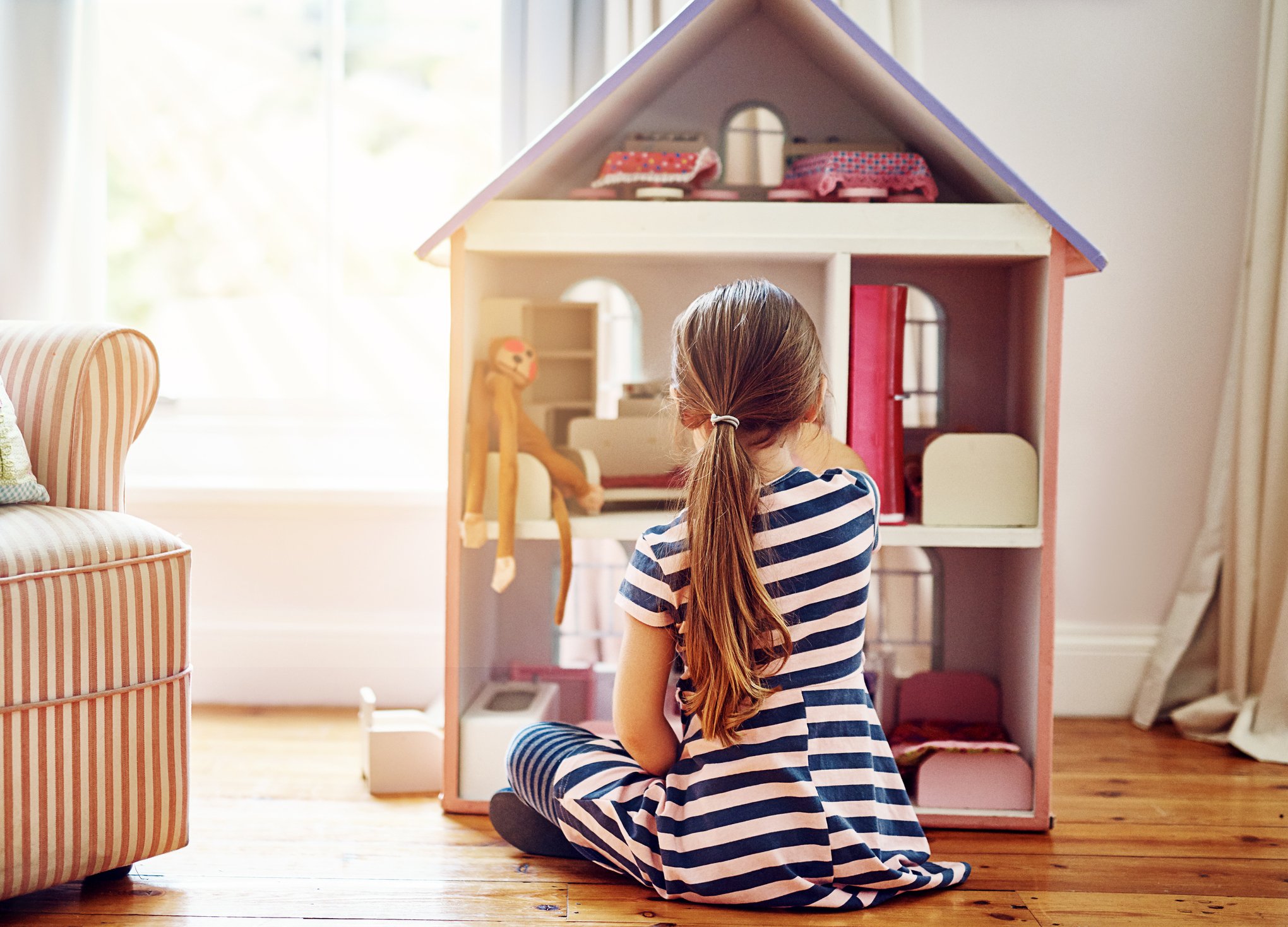 A child playing with a dollhouse.