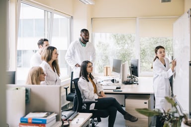 scientist writes on whiteboard in meeting