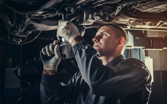 A mechanic repairs a car in an auto repair shop.