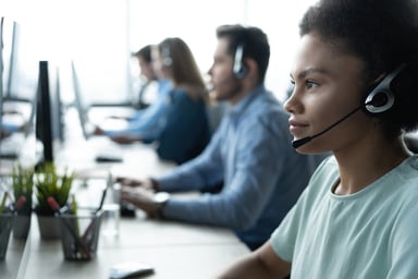 Numerous call center operators wearing headphones.