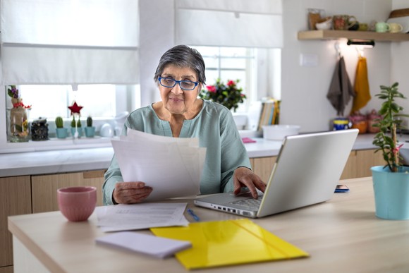 Older person looking at documents at the kitchen table. 