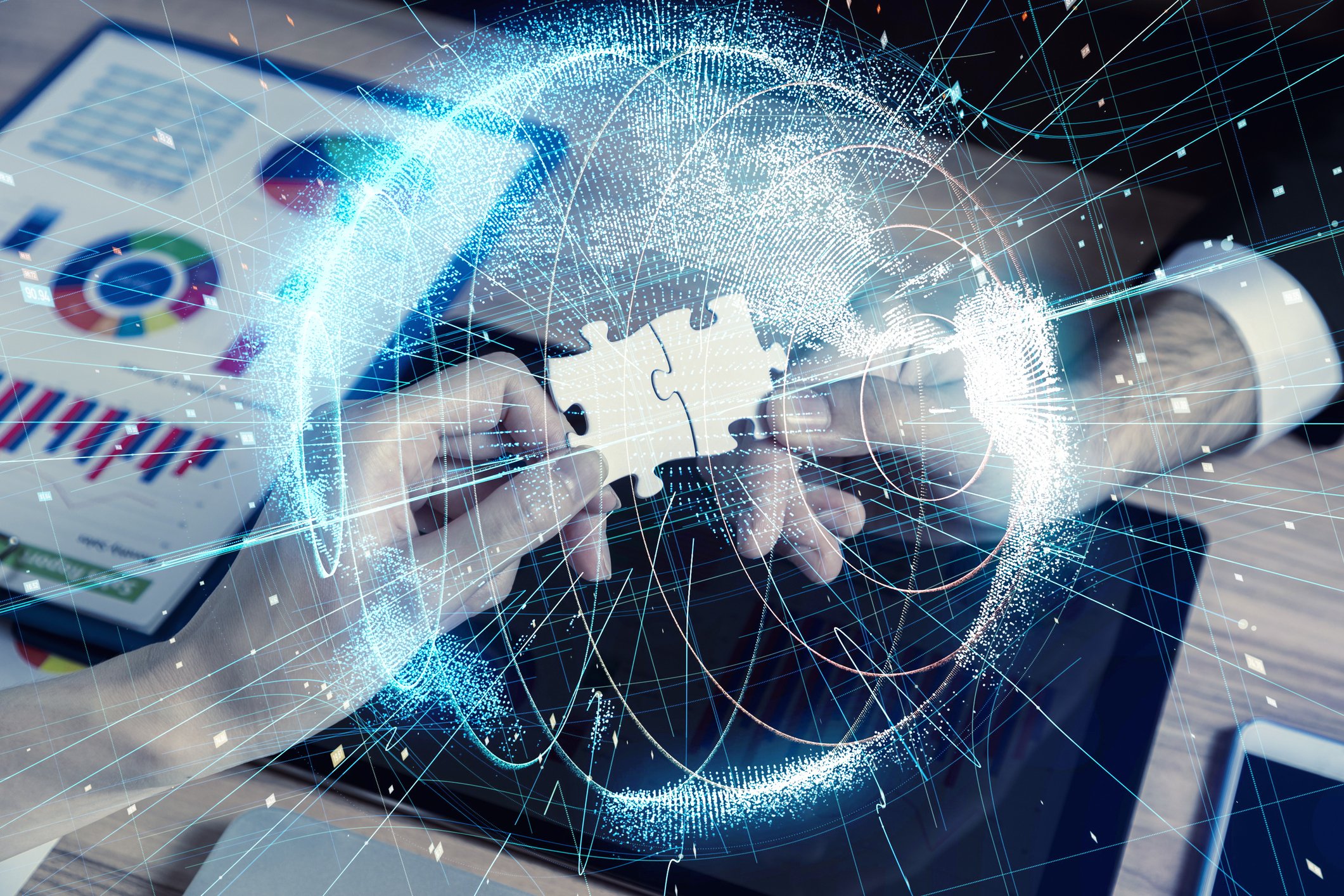 Two hands connect two puzzle pieces with tech graphs and animations around it.  