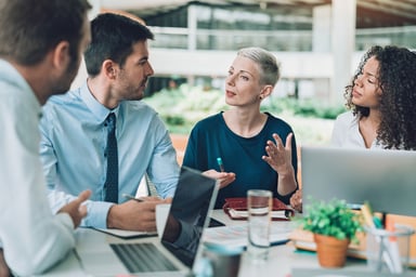 businesspeople sit around table talking