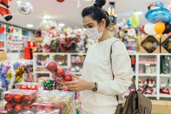 Person in mask shopping for Christmas decorations.