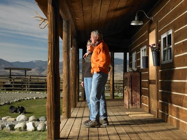 people stand on porch overlooking farm
