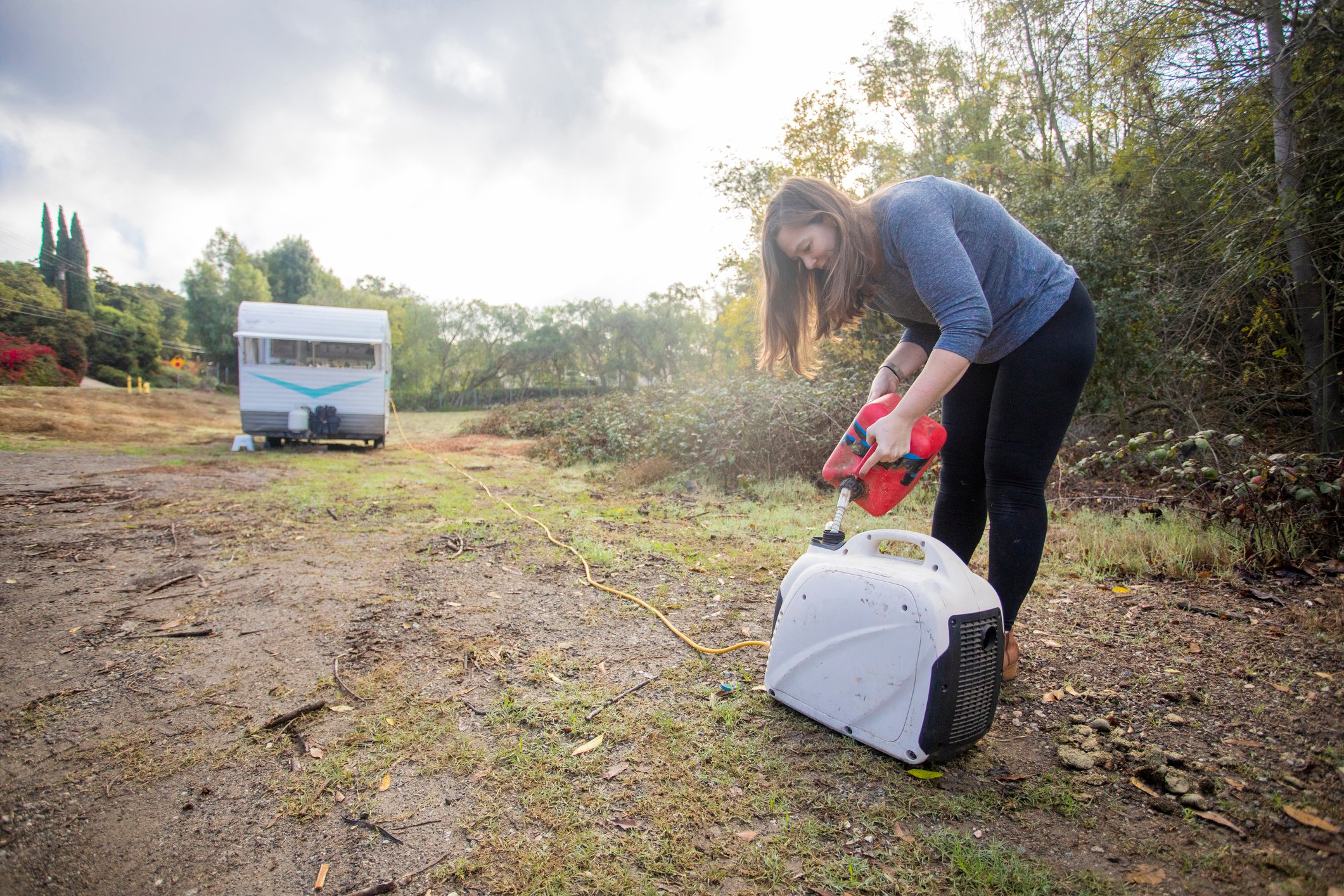 A woman pours gas into a generator.