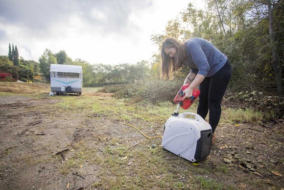 A woman pours gas into a generator.