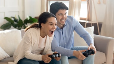 Two people sitting on sofa and playing video game