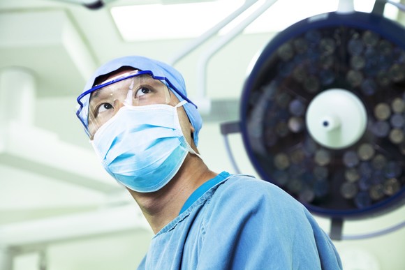 Surgeon in operating room wearing a mask and glasses.
