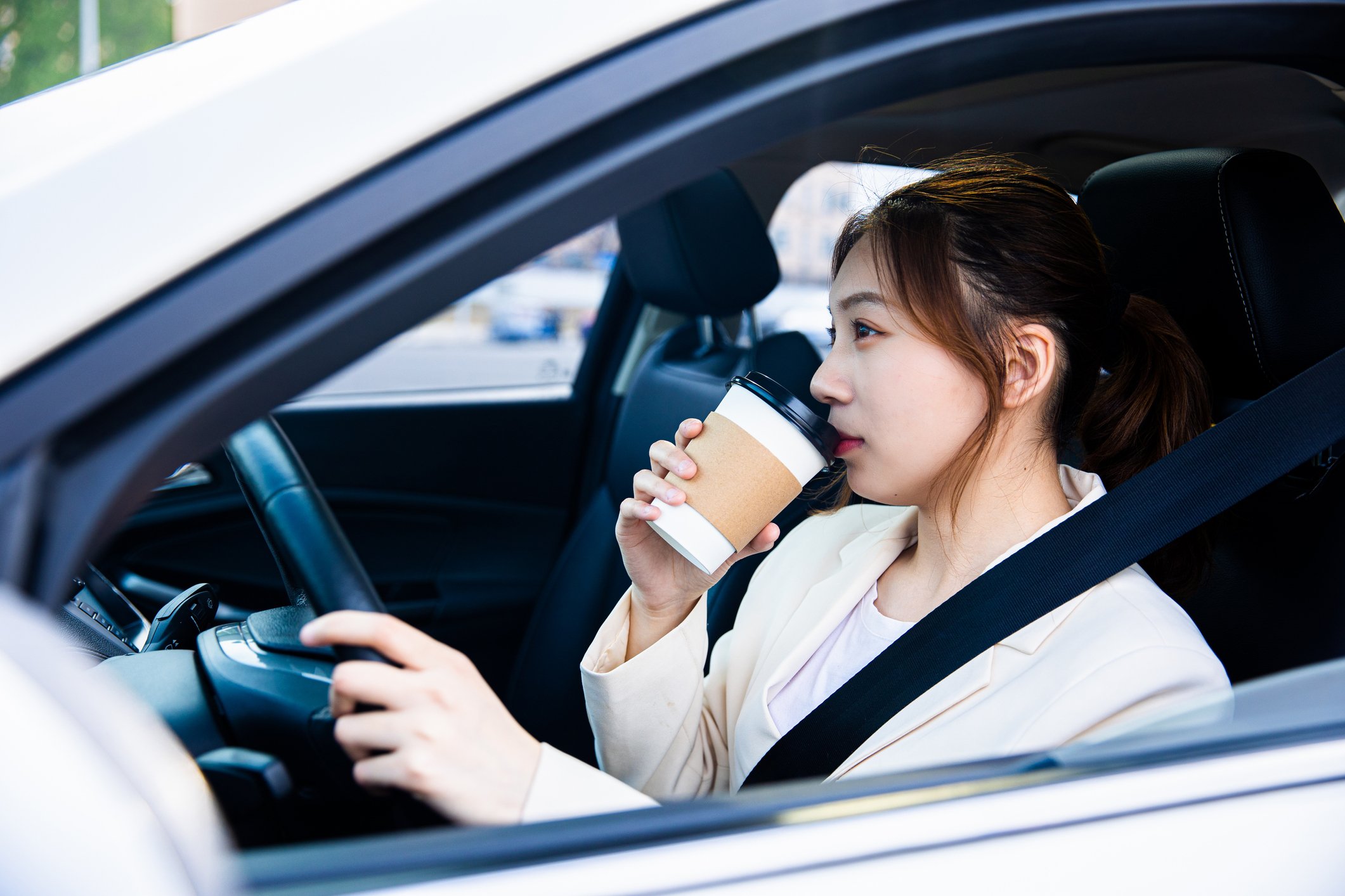 A person drinking coffee while driving in a car.