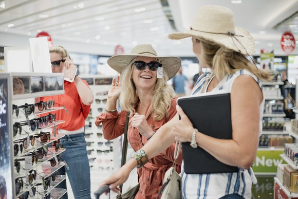 Shoppers having fun trying on sunglasses in a store.