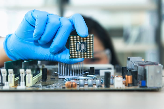 A hand holds up a computer chip.