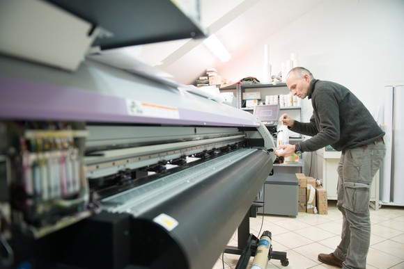 A worker cleans a large printing press.