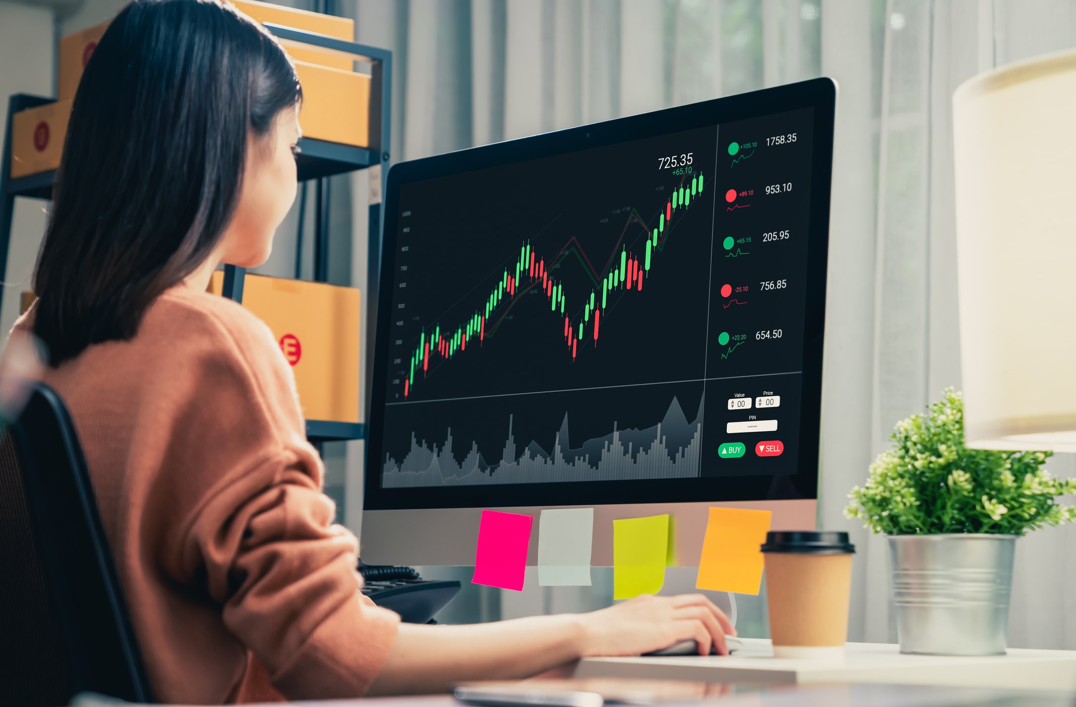 Woman using her computer to monitor a cryptocurrency price chart.