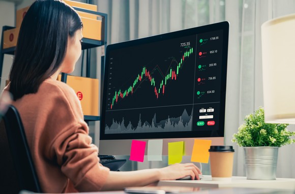 Woman using her computer to monitor a cryptocurrency price chart.