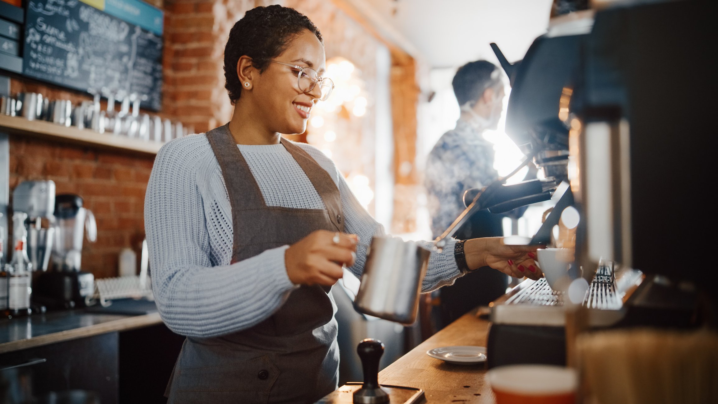 Barista steaming milk in a coffee shop.