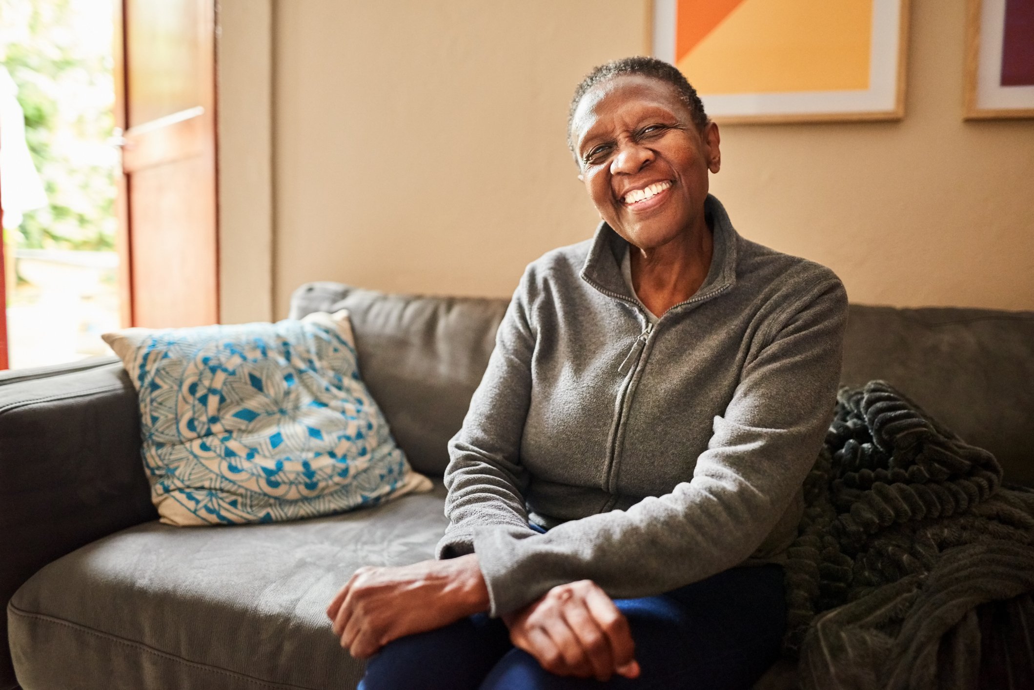Person smiling at camera sitting on couch.