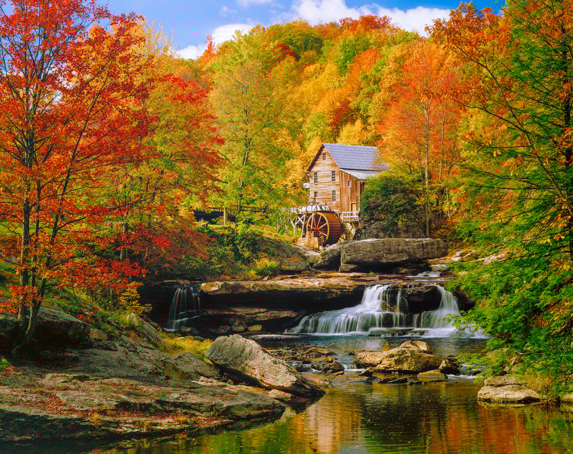 Cabin with river and waterfall in mountains.